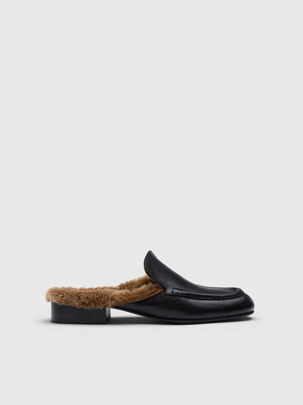A single black leather slip-on loafer with a brown shearling lining, shown in a side profile against a light gray background.