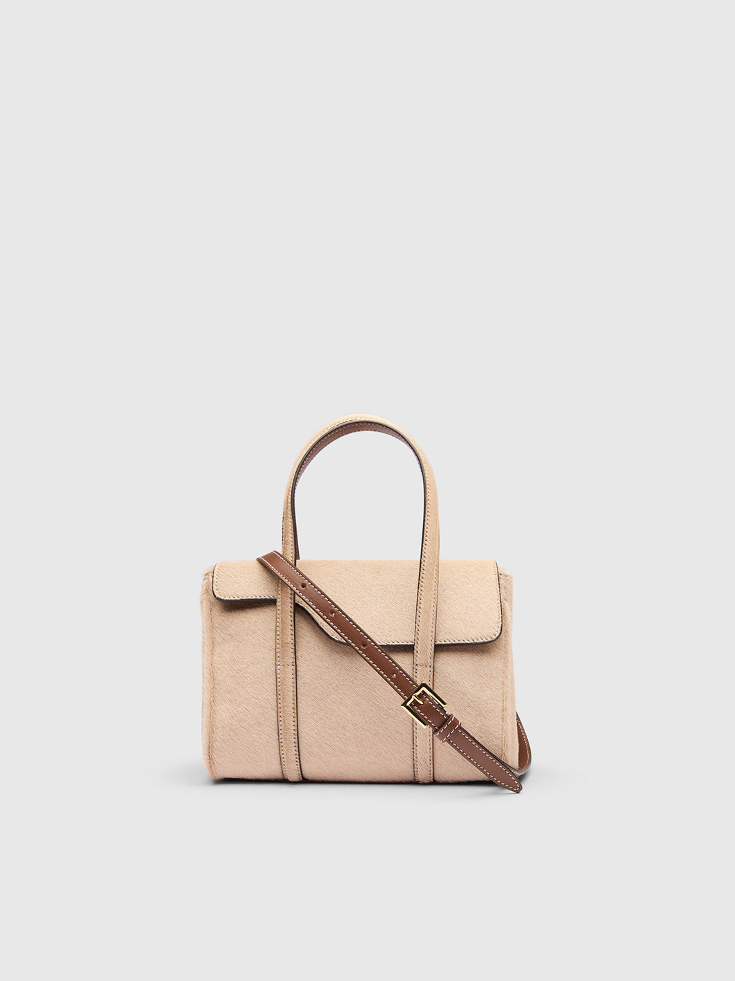 A structured beige top-handle handbag with a brown shoulder strap and gold-tone buckle, shown against a light gray background.