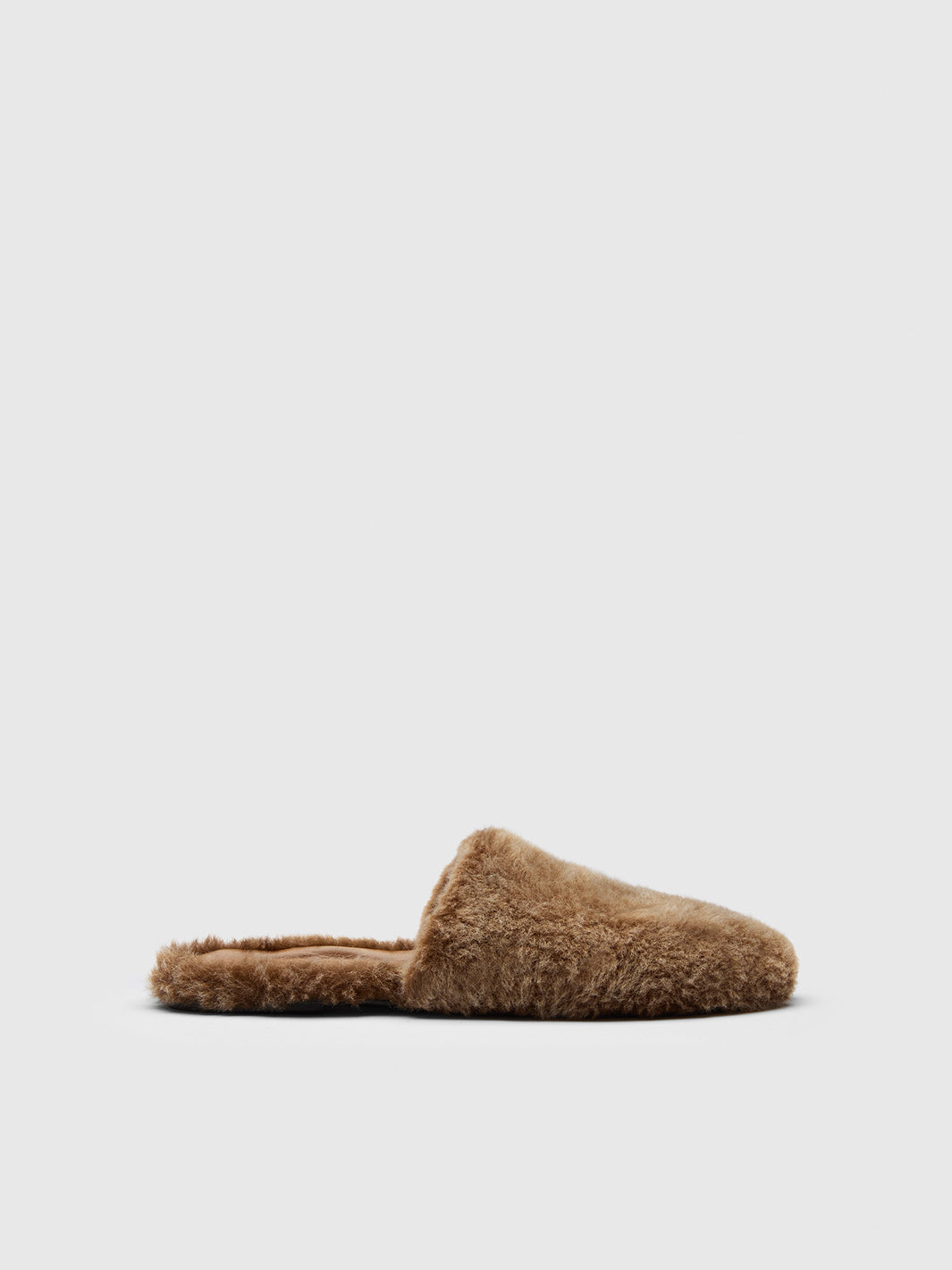 A single sand-brown fuzzy slip-on mule slipper shown in side profile against a light gray background.