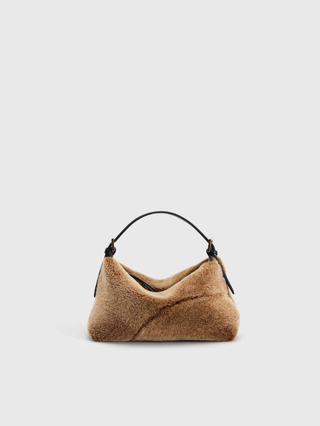 A small slouchy shoulder bag made of textured tan faux fur with a black leather handle, shown against a solid light gray background.